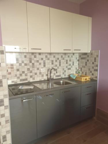 a kitchen with white cabinets and a sink at Apartments Drago in Petrcane