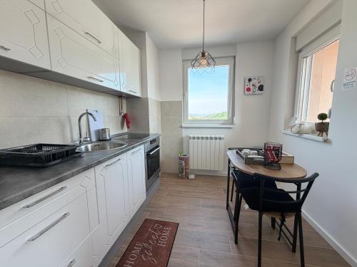 a kitchen with white cabinets and a table and a sink at Apartment Alto in Sarajevo