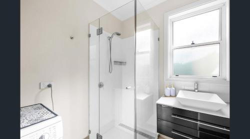 a white bathroom with a sink and a shower at Fitzroy Cottage one bedroom CBD accommodation in Tamworth