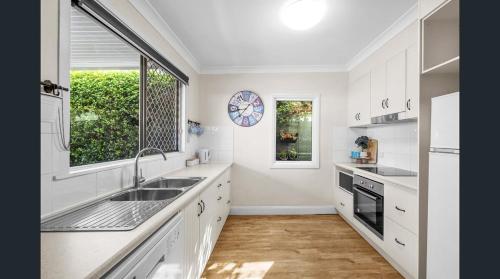 a kitchen with white cabinets and a sink and a window at Fitzroy Cottage one bedroom CBD accommodation in Tamworth