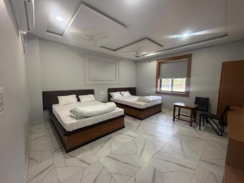 a room with two beds and a table and a window at Seasons Resorts in Jabalpur