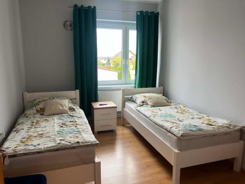 two beds in a room with green curtains and a window at Pod Kogucikiem in Krzyżanowice