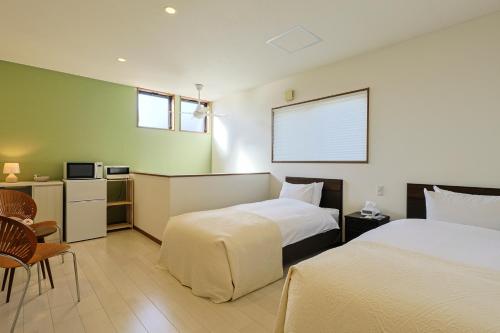 ein Hotelzimmer mit zwei Betten und einem Fernseher in der Unterkunft Shushu in Asago