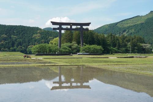 a torii gate in a field next to a body of water at SEN RETREAT HONGU - Kumano Kodo Gateway in Tanabe