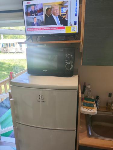 a flat screen tv on top of a refrigerator at MOBIL-HOME n 95 in Barrême
