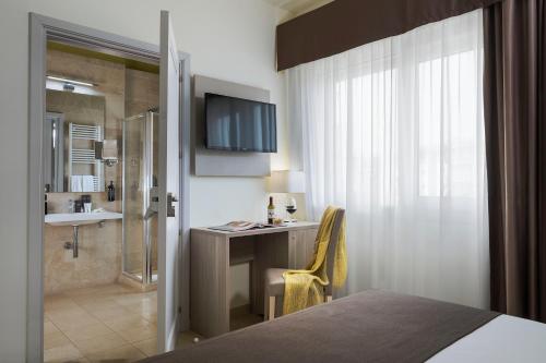 a hotel room with a bed and a desk and a shower at Netum Hotel in Noto