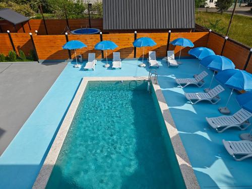 a swimming pool with chairs and umbrellas and a group of chairs and tables at Golden Coast in Batumi