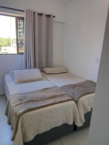 two twin beds in a room with a window at Alugo QUARTO em Apartamento -Centro de Recife in Recife