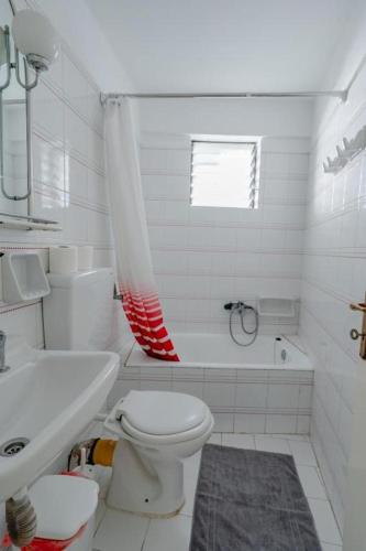 a white bathroom with a toilet and a sink at Blue Lemon Hideaway in Poros