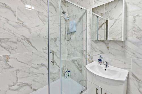 a white bathroom with a shower and a sink at Nile - Cosy Studio Apartment by Traboule Properties Ltd in Warrington