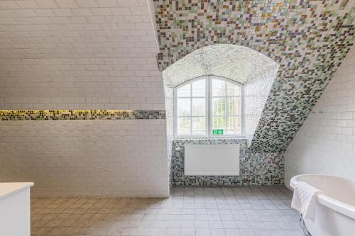 a bathroom with a window and a bath tub at Söderfors Herrgård in Söderfors