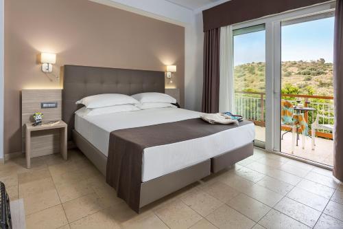 a bedroom with a large bed and a balcony at Netum Hotel in Noto