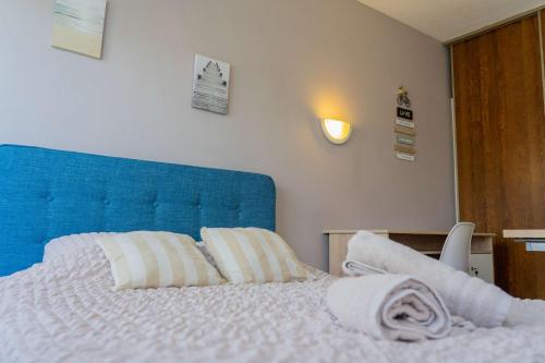 a bed with a blue headboard and two white pillows at Appart-Hotel du drapeau bleu Residence Kiwi in Aytré