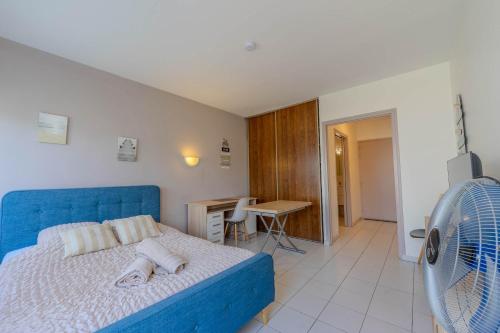 a bedroom with a blue bed and a desk and a fan at Appart-Hotel du drapeau bleu Residence Kiwi in Aytré