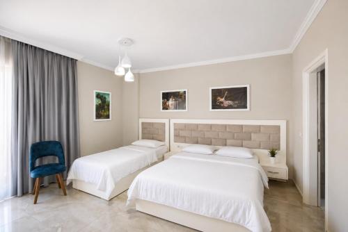 two beds in a white room with a blue chair at Hotel Mare in Ksamil