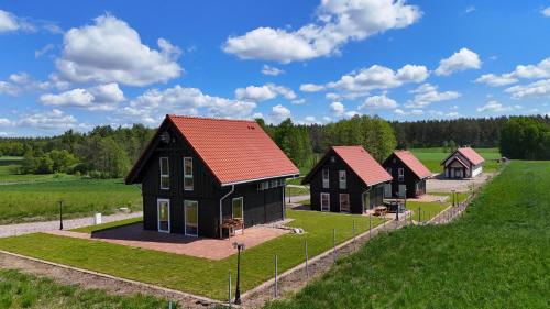 a group of houses in a grassy field at Suwalskie Klimaty in Kaletnik