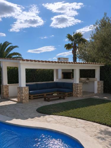 a pergola with a blue couch and a pool at Casa Lluna De Mar in L'Ampolla