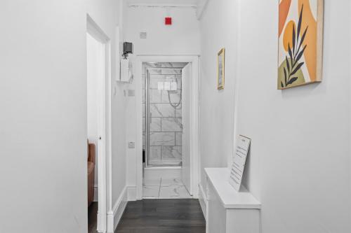 a hallway with white walls and a door with a sign at Tigris - Cosy Studio Apartment by Traboule Properties Ltd in Warrington