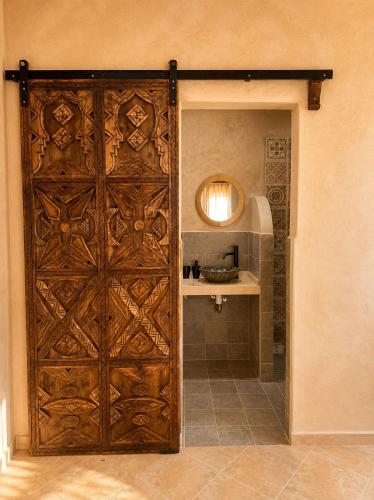 an entrance to a bathroom with a wooden door at Yara Lodge in Tamraght Ou Fella