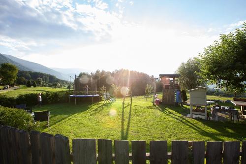 a field with a playground with the sun in the background at Hölzlhof in Brunico