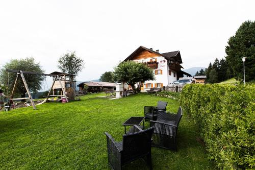 a group of chairs in a yard with a playground at Hölzlhof in Brunico