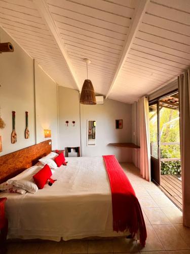 a bedroom with a large white bed with red pillows at Pousada Ilha do Frade in Fernando de Noronha
