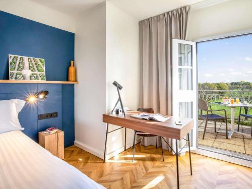 a hotel room with a desk and a balcony at Mercure Chantilly Resort & Conventions in Chantilly