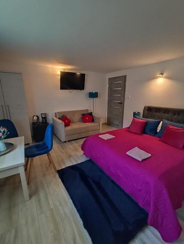 a bedroom with a large pink bed and a couch at Pokoje Koral in Mikołajki
