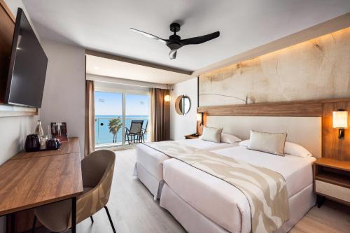 a hotel room with a large bed and a desk at Hotel Riu Palace Nautilus - Adults Only in Torremolinos