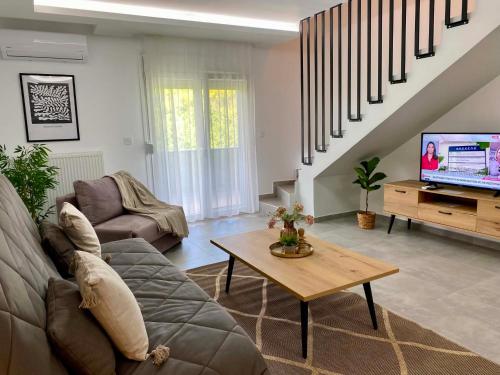 a living room with a couch and a tv at Margarita's apartment 4 in Nea Peramos
