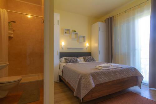 a bedroom with a bed and a bathroom with a tub at Apartments & Rooms Sanja in Rab