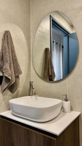 a bathroom sink with a round mirror above it at Melinda’s cozy apartments in Plomari