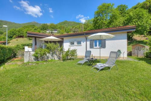 two chairs and an umbrella in the yard of a house at La Cà Da Brè - Garden House with Views - Happy Rentals in Lugano