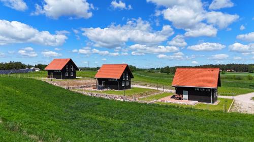 two buildings with red roofs on a green field at Suwalskie Klimaty in Kaletnik