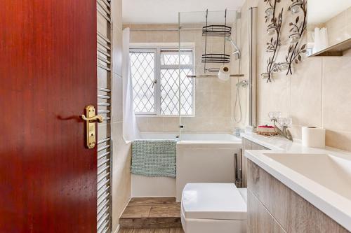 a bathroom with a toilet and a sink and a window at Rest & Nest in Chelsfield