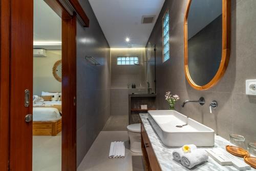 a bathroom with a sink and a toilet and a mirror at Pondok Tis Bisma in Ubud