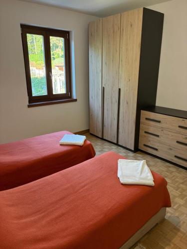 a bedroom with two beds and a dresser and a window at Casa RIGPA in Bellagio