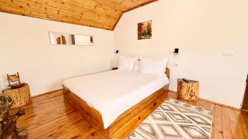 a bed in a room with white walls and wooden floors at Casa de sub Horă in Zărneşti