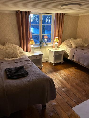 a bedroom with two beds and a window and two lamps at Kanalhuset in Motala
