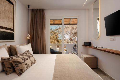 a hotel room with a bed with a large window at Ammolofos Luxury Apartment & suites in Naxos Chora
