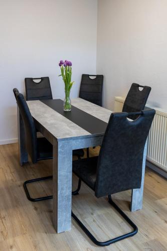 a table with chairs and a vase of flowers on it at Auszeit im Sauerland in Meschede
