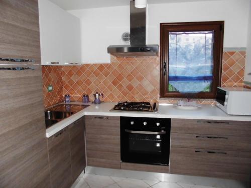 a kitchen with a stove and a window in it at Casa vacanze Villa Lucheria Loceri in Loceri