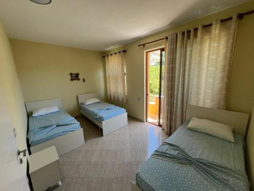 a room with two beds and a door to a balcony at Rigandi in Durrës