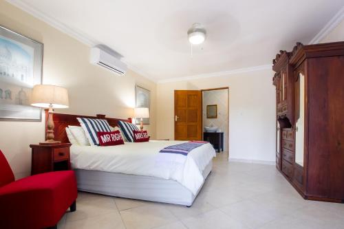 a bedroom with a large white bed and a red chair at Turtle Bay Lodge in St Lucia