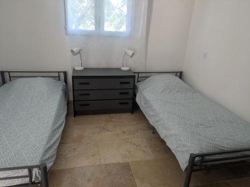 two beds in a bedroom with a dresser and a window at Maison moderne et lumineuse in Cavaillon