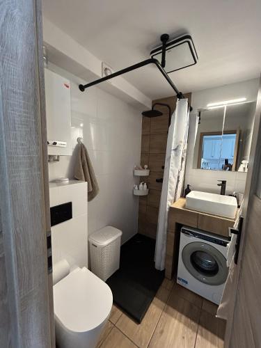 a bathroom with a toilet a sink and a washing machine at Apartament Drzymały in Lubin