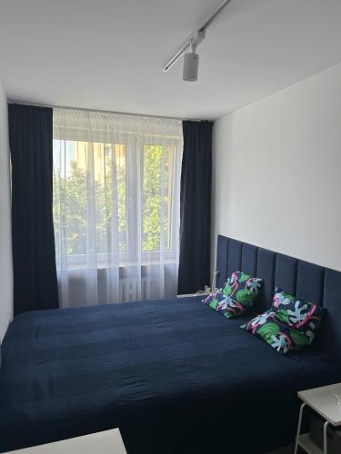 a bedroom with a blue bed with a window at Apartament Drzymały in Lubin