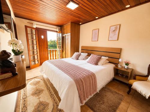 a bedroom with a large bed and a chair at Flats Morada do Jordão in Campos do Jordão
