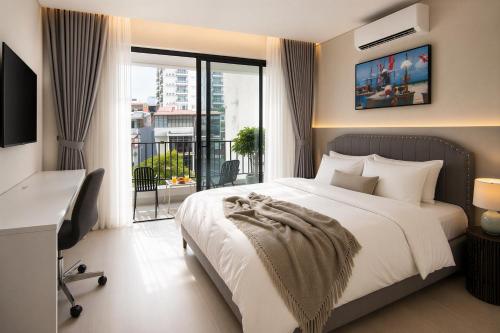 a bedroom with a bed and a desk and a window at Centraltique Veranda Living in Hanoi