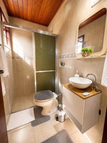 a bathroom with a toilet and a sink and a shower at Flats Morada do Jordão in Campos do Jordão